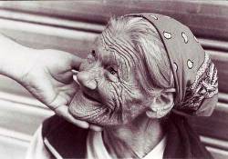 Una mano affettuosa accarezza il volto di una donna anziana